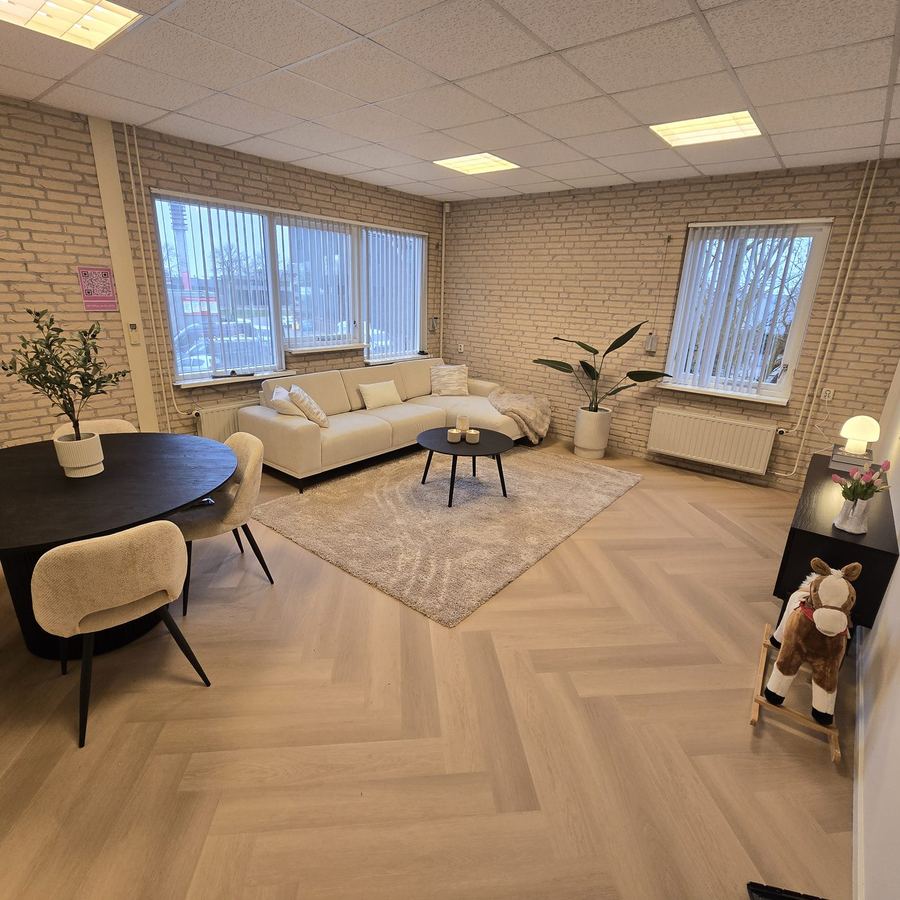 Huiselijk ingerichte ruimte met een bank, een eettafel en een visgraatvloer.
